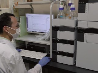 加工技術部の職員が水産物の鮮度保持について研究するために機器を操作して成分を分析している写真