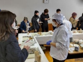 展示試食会で試作品を来所者に試食してもらいながら、加工技術部の職員が試作品について説明している写真